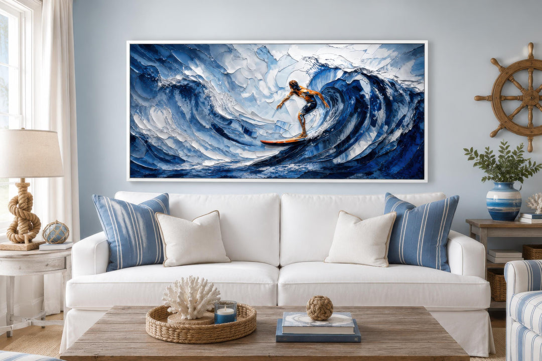 A wide horizontal canvas print of a surfer on a large blue wave in a coastal living room.
