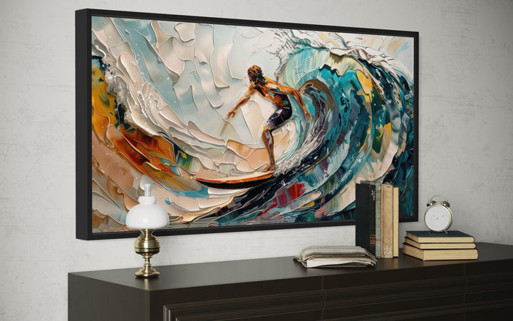 Abstract canvas wall art of a surfer riding a vibrant, textured ocean wave in a black frame.