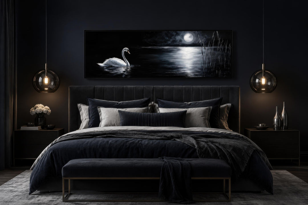 Swan in moonlit lake long narrow canvas print above a dark upholstered bed in a moody bedroom.