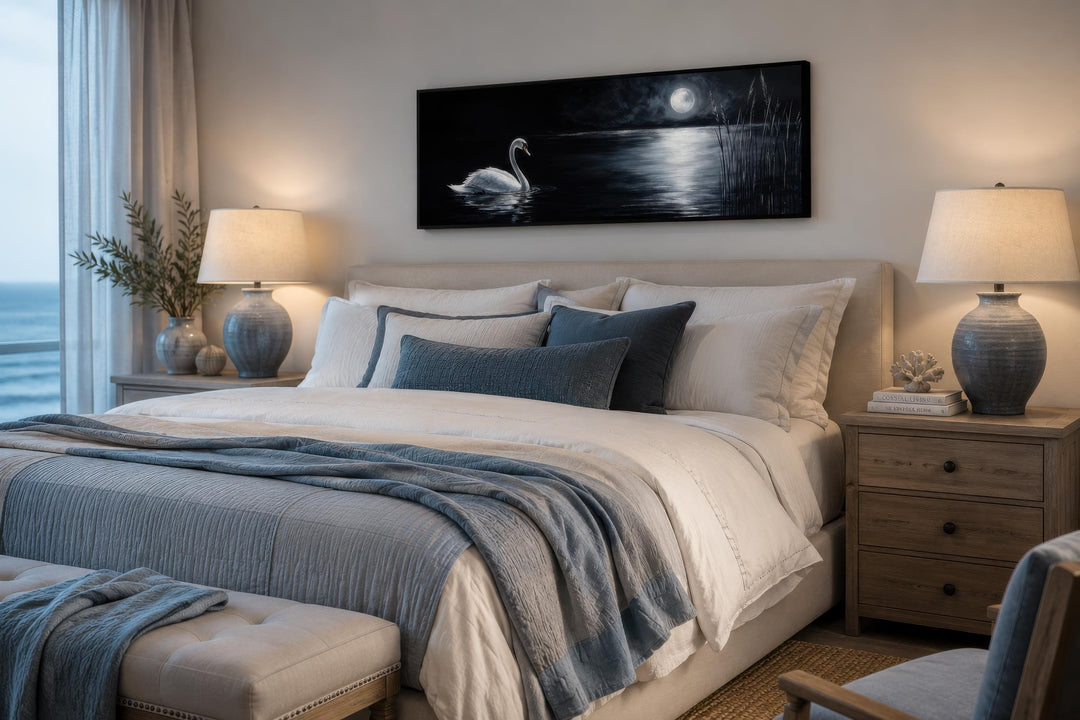 Long narrow canvas print of a white swan on a moonlit lake above a bed in a moody bedroom.