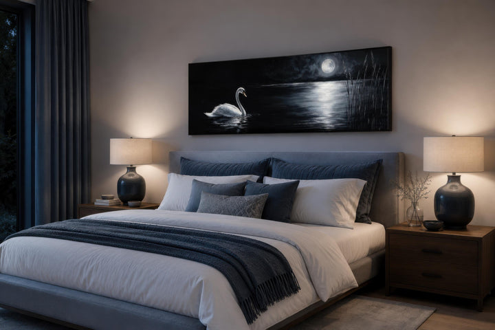 Long narrow canvas print of a white swan on a moonlit lake above a bed in a moody bedroom.