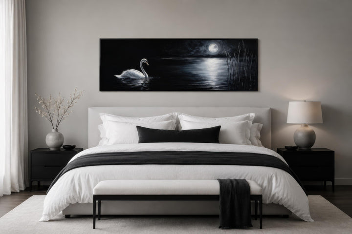 Long narrow canvas print of a white swan on a dark lake under a full moon above a modern bed.