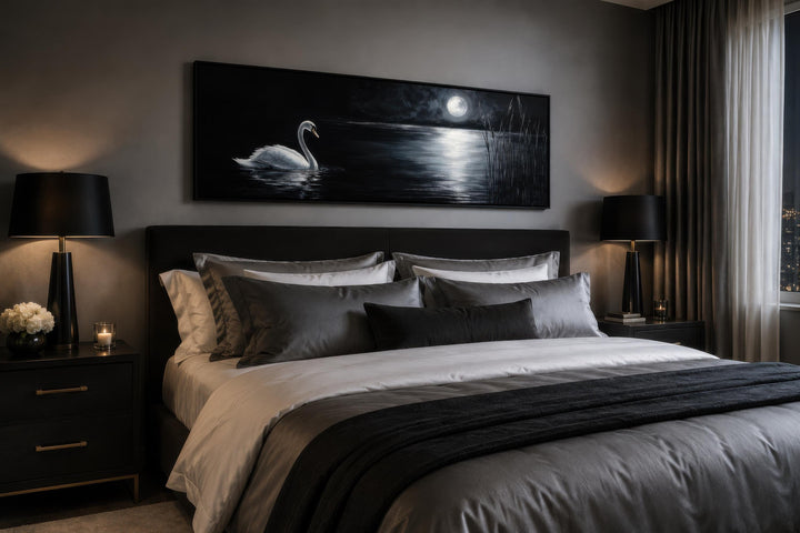 Long narrow canvas print of a white swan on a moonlit lake above a bed in a dark moody bedroom.
