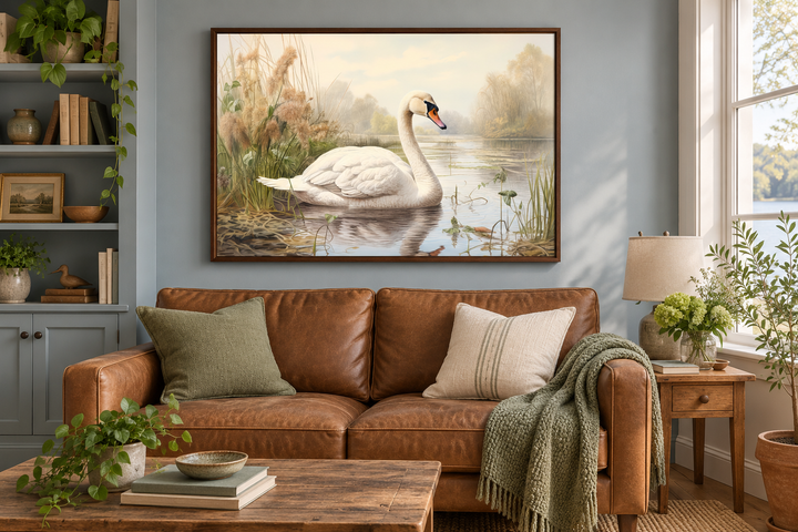 Framed vintage-style canvas art of a white swan on a lake, hung above a brown leather sofa.