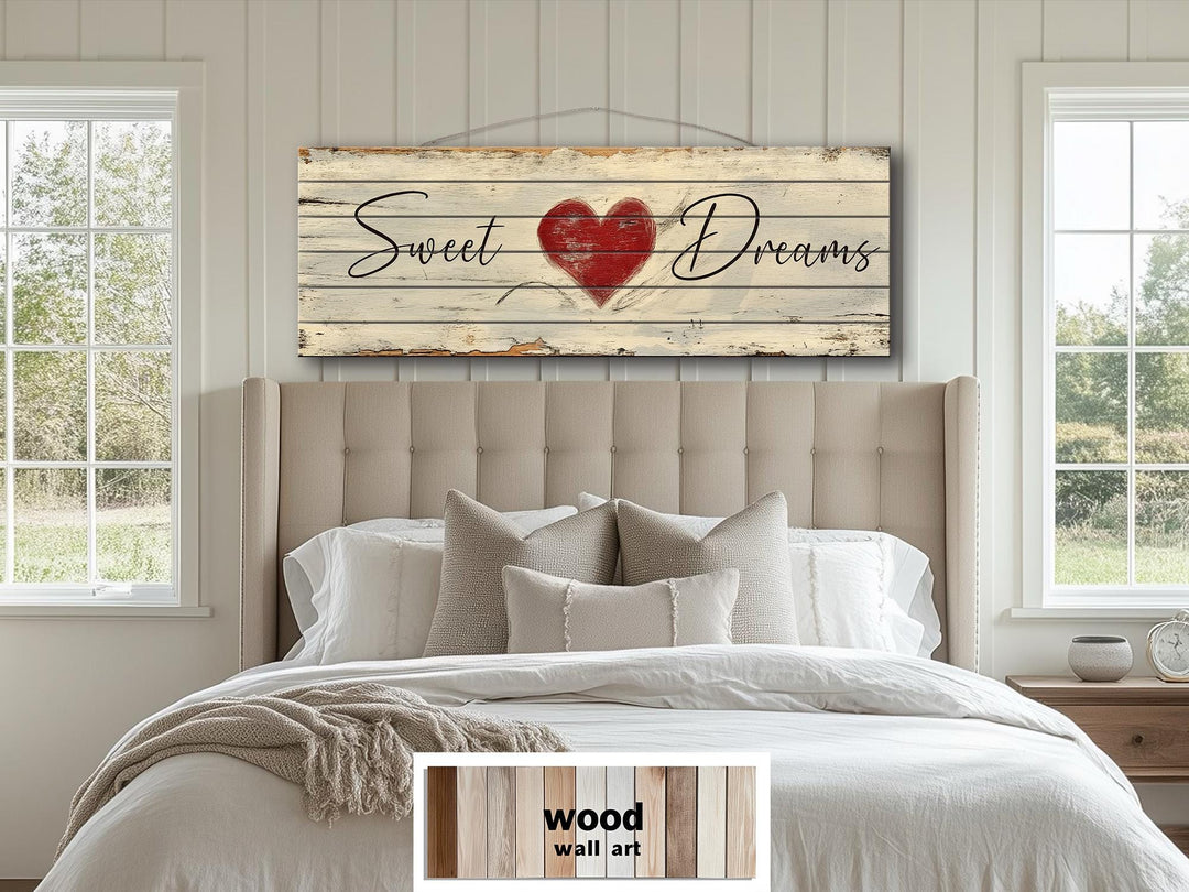 A rustic wood wall sign with Sweet Dreams and a red heart hangs above a bed in a farmhouse bedroom.