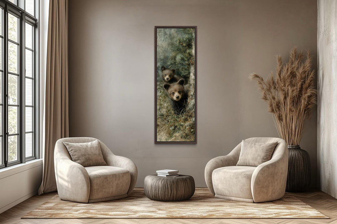 Tall narrow canvas wall art of two baby bear cubs peeking from a pine tree in a rustic living room.