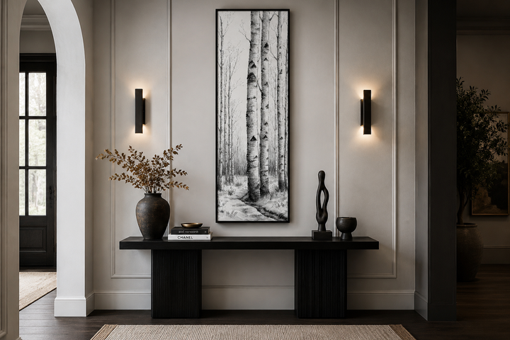 Tall narrow vertical framed canvas wall art featuring black and white birch trees in a winter scene.