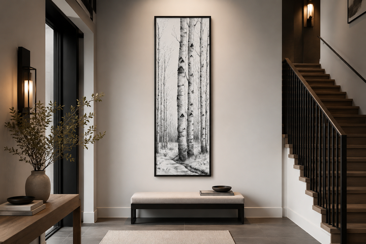 Tall narrow vertical framed canvas wall art featuring black and white birch trees in a winter scene.