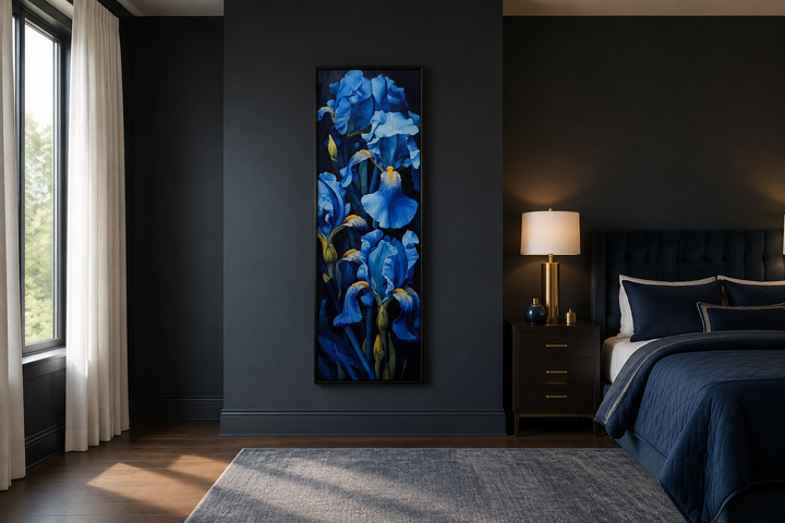 Tall narrow framed canvas wall art featuring vibrant blue irises on a black background in a bedroom.