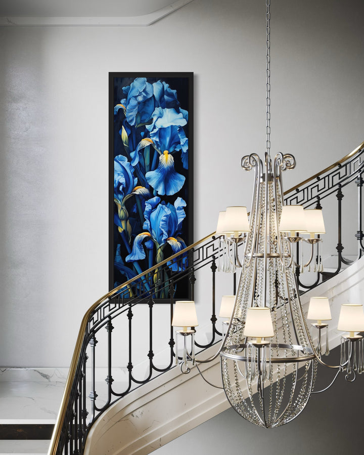 Tall narrow framed canvas wall art featuring blue irises on a black background in a stairwell.