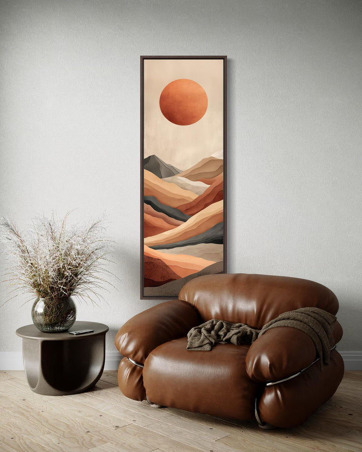 Tall narrow vertical canvas print of a terracotta desert landscape with a sun and mountains.