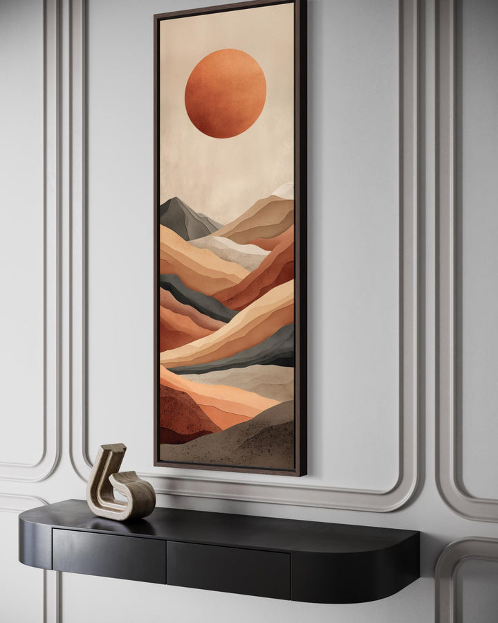 Vertical canvas print of a terracotta desert landscape with a large sun in a modern interior.