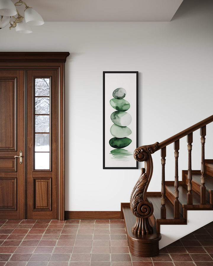 Tall Narrow Forest Green White Stacked Rocks Vertical Framed Canvas Wall Art hanging on a wall next to a stair case