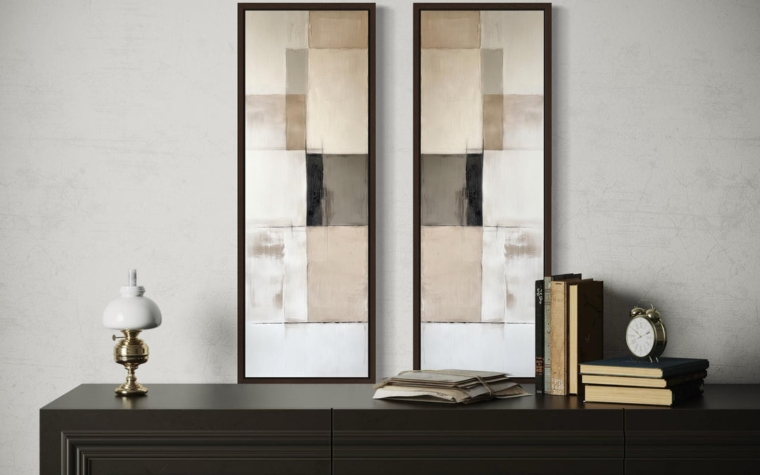 Narrow geometric neutral abstract set of 2 canvas wall art in tall frames on a dark console table.