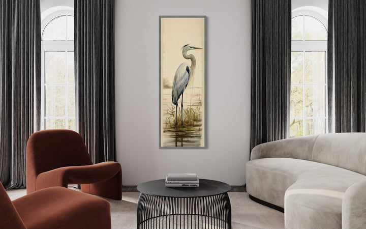 Tall narrow framed canvas wall art featuring a great egret in a modern living room setting.