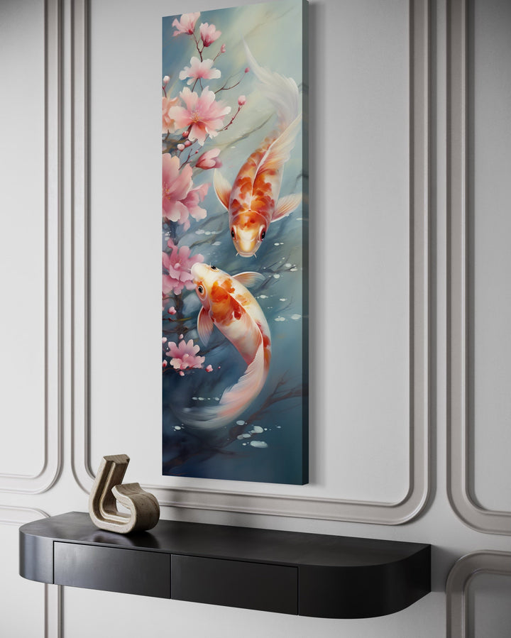 Tall narrow vertical canvas wall art featuring two koi fish swimming among pink cherry blossoms.
