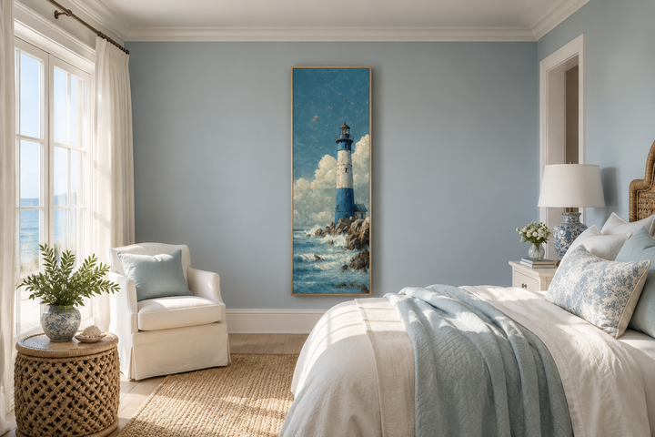Tall slim lighthouse canvas wall art in a coastal bedroom with blue walls and white furniture.