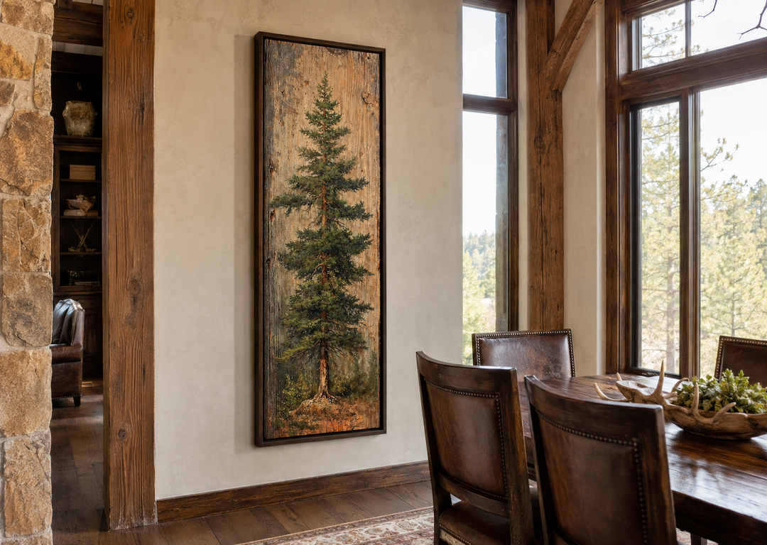 Tall vertical fir tree canvas wall art in a dark frame, hanging in a rustic cabin dining room.