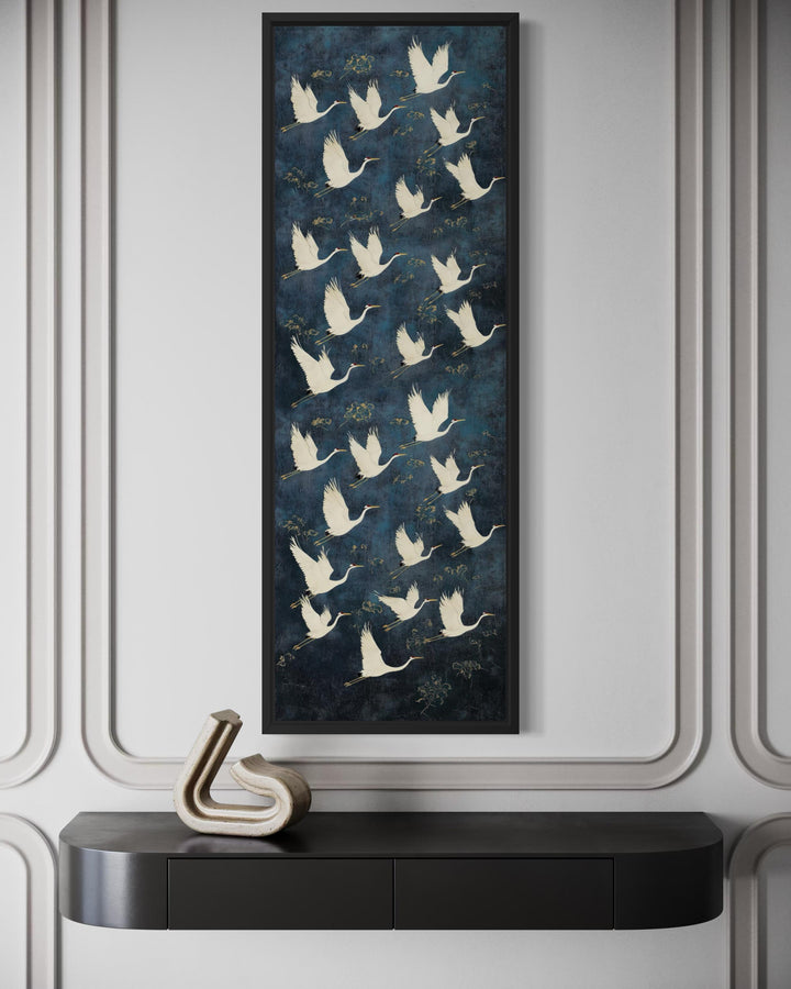 Tall vertical navy canvas wall art featuring white flying cranes above a black console table.
