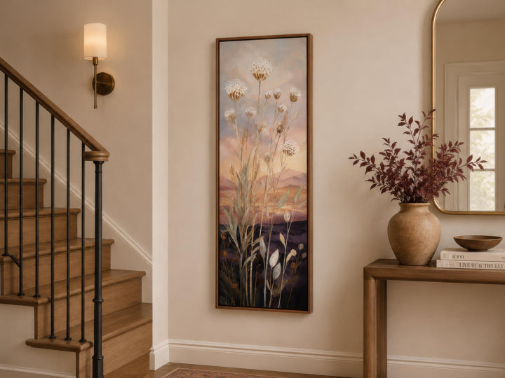 Tall vertical wildflower sunset wall art in a wood frame, hanging in a neutral-toned entryway.