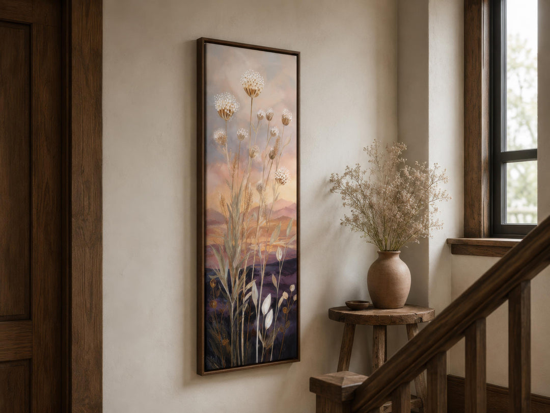 Tall vertical canvas wall art of wildflowers against a gold and purple sunset in a wooden frame.