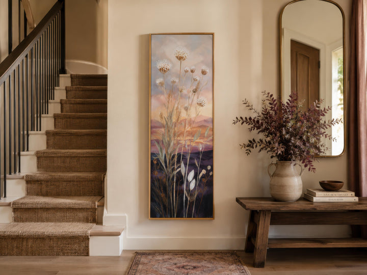 Tall vertical canvas art of wildflowers against a gold and purple sunset in a home entryway.