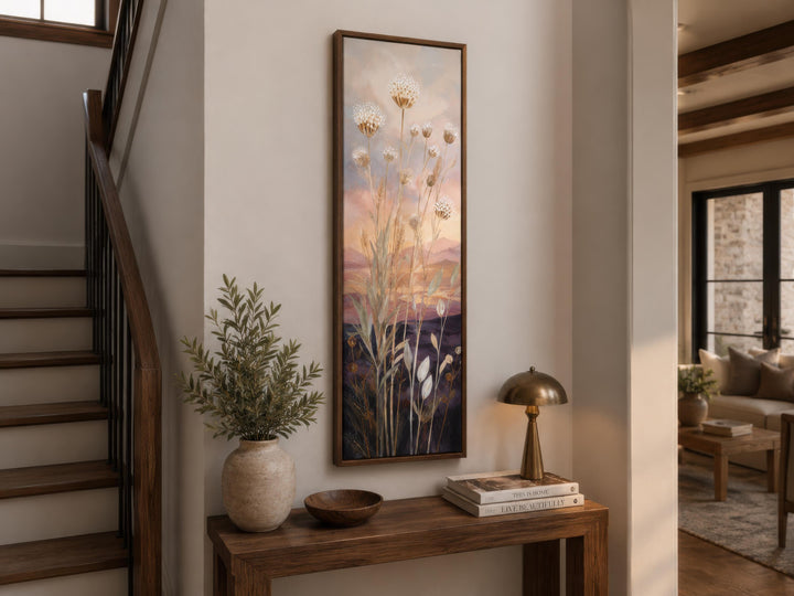 Tall vertical canvas art of wildflowers against a gold and purple sunset in a wooden frame.