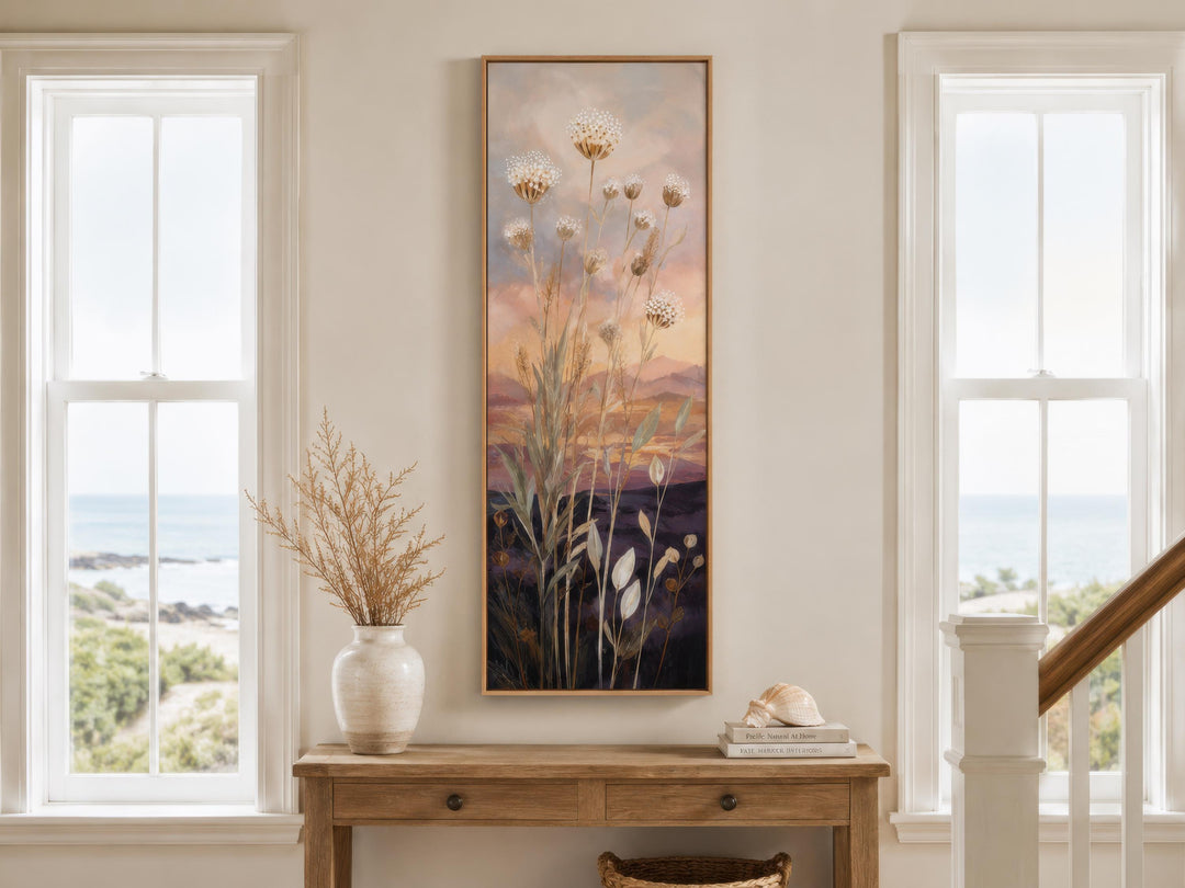 Tall vertical canvas art of wildflowers against a gold and purple sunset above a wooden console.