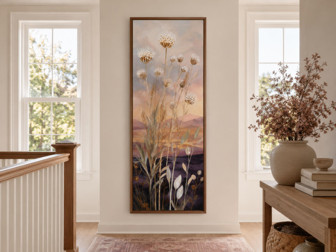 Tall vertical canvas art of wildflowers against a gold and purple sunset in a wooden frame.