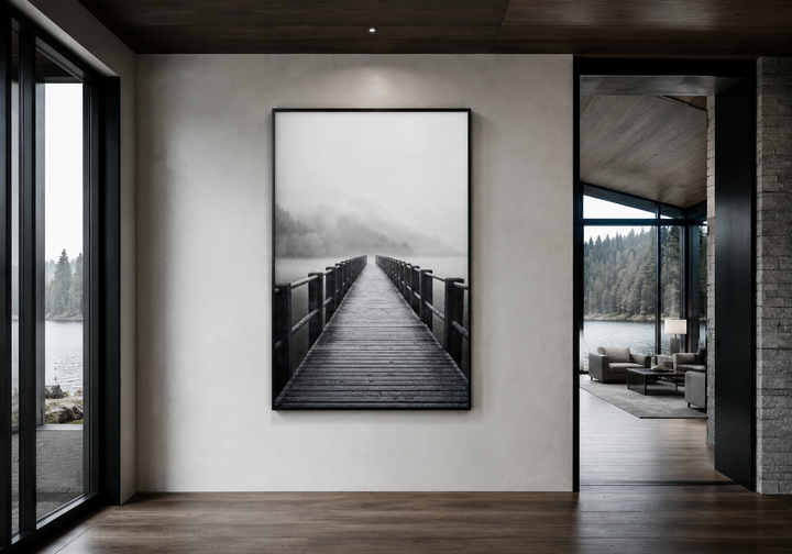 Vertical black and white framed canvas art of a foggy lake and wooden pier on a modern white wall.