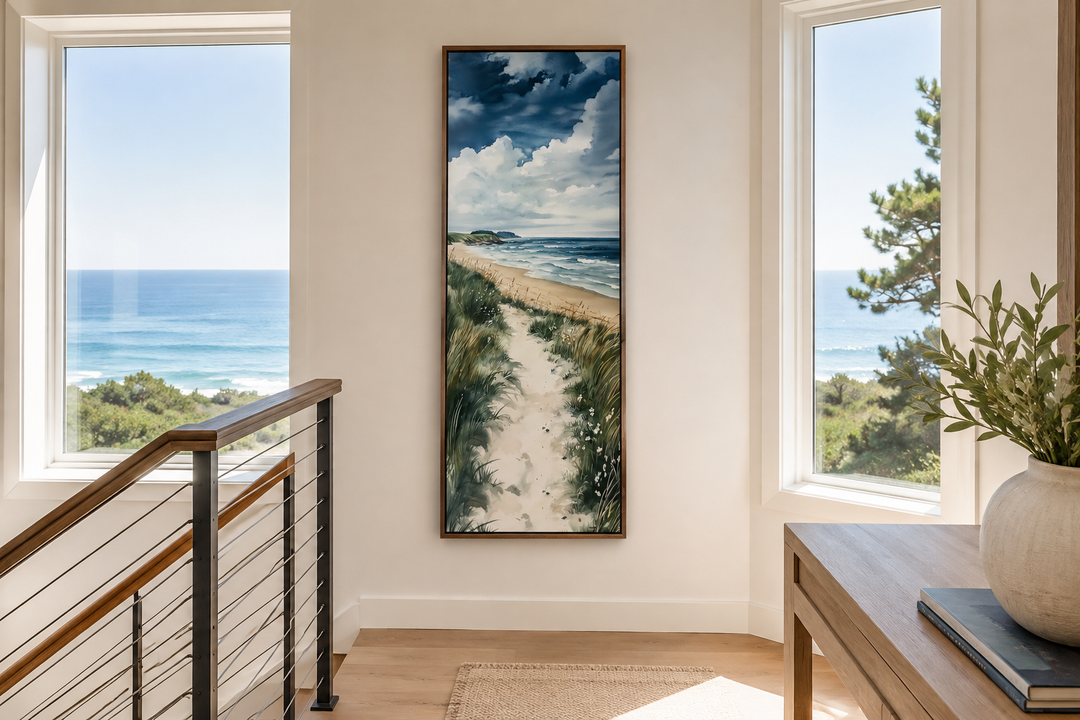 Tall narrow framed canvas wall art of a coastal seashore with sand dunes, grass, and blue ocean.