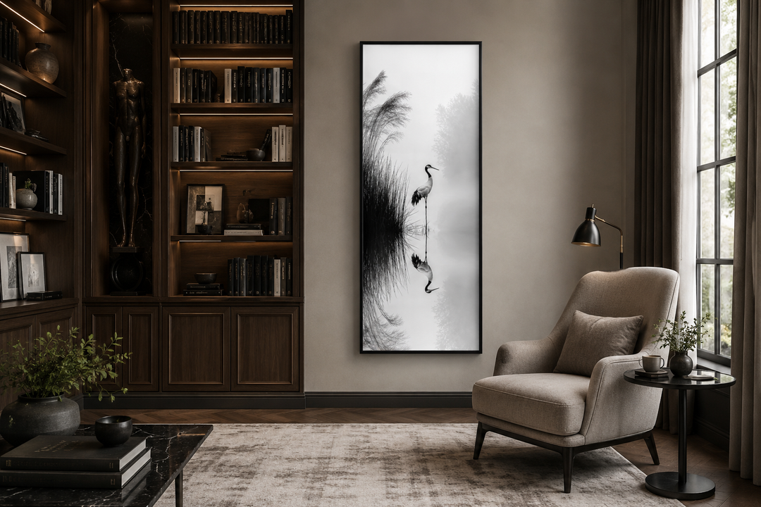 Tall narrow black and white Japanese crane wall art in a zen-style living room with a reading chair.
