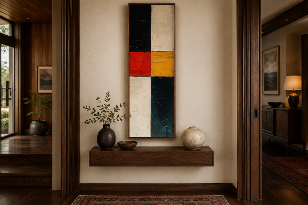 Tall narrow vertical canvas art with geometric blocks of black, white, red, and yellow on a wall.