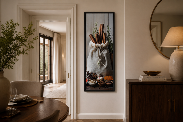 Tall narrow vertical framed canvas wall art featuring a sack of cinnamon sticks and various spices.