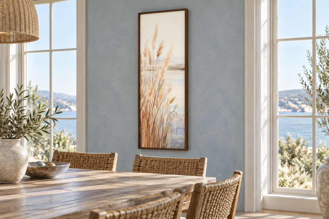 Vertical framed canvas art of pampas grass on a beach, hung in a coastal dining room.