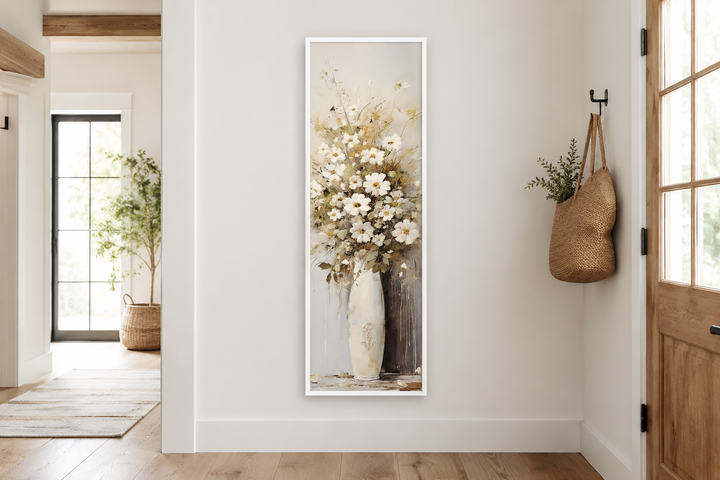 Tall narrow framed canvas wall art of white wildflowers in a vase in a farmhouse entryway.