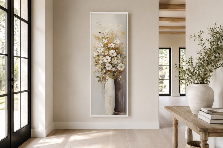 Tall narrow framed canvas art of white wildflowers in a vase on a neutral farmhouse wall.