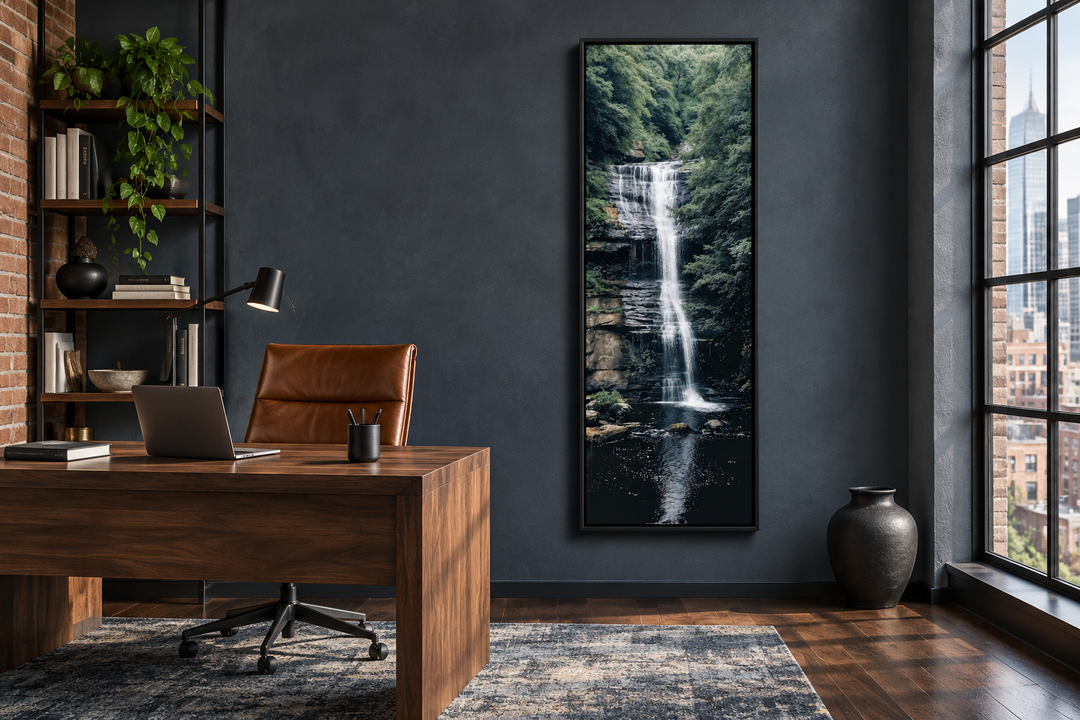 Tall narrow vertical framed canvas wall art of a serene waterfall in a dark modern office setting.
