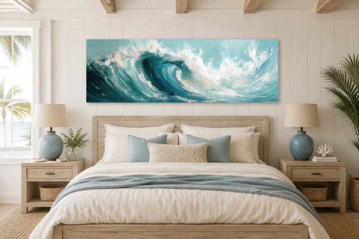 Teal ocean wave panoramic framed canvas wall art hanging over a bed in a coastal style bedroom.