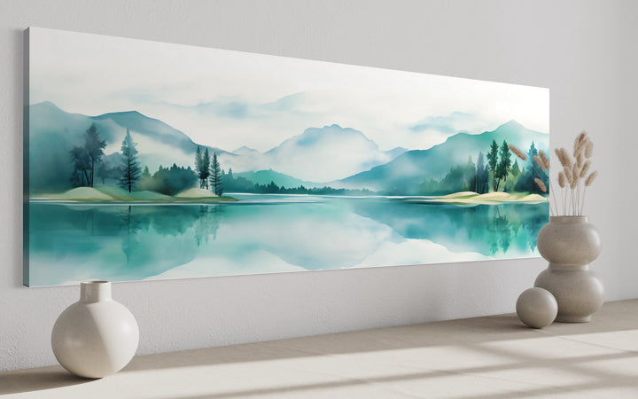 Teal watercolor panoramic wall art featuring a mountain and lake landscape above a bed.