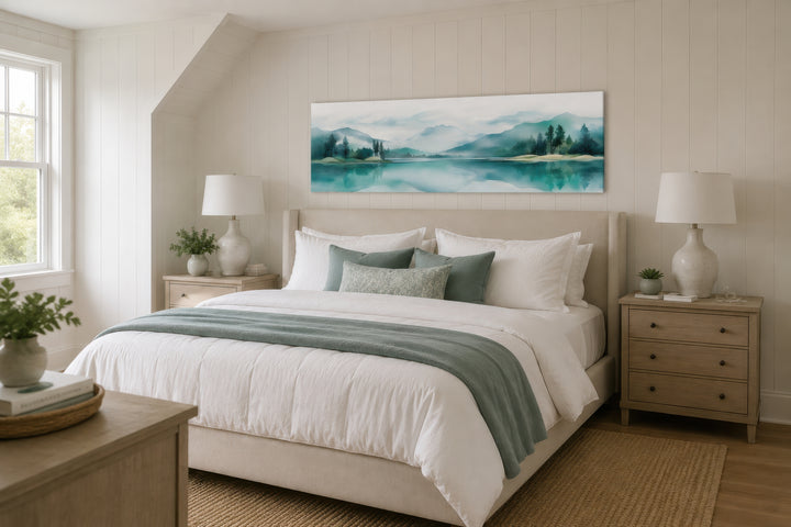 Teal watercolor mountain and lake landscape panoramic wall art hanging above a bed.