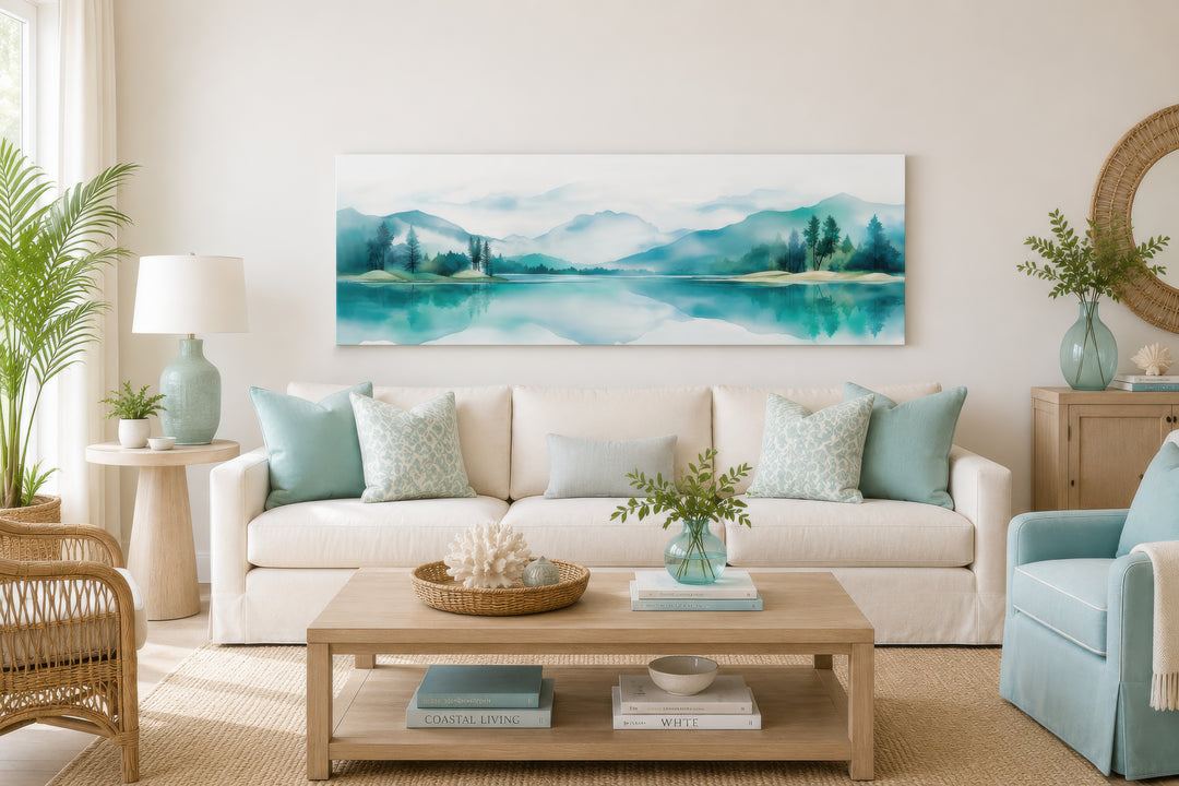 Teal watercolor mountain and lake landscape panoramic wall art hanging above a white sofa.