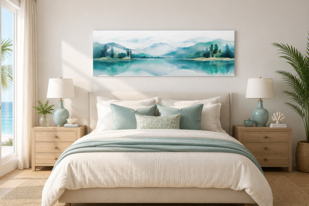 Teal watercolor mountains and lake landscape long narrow canvas art displayed over a bed.