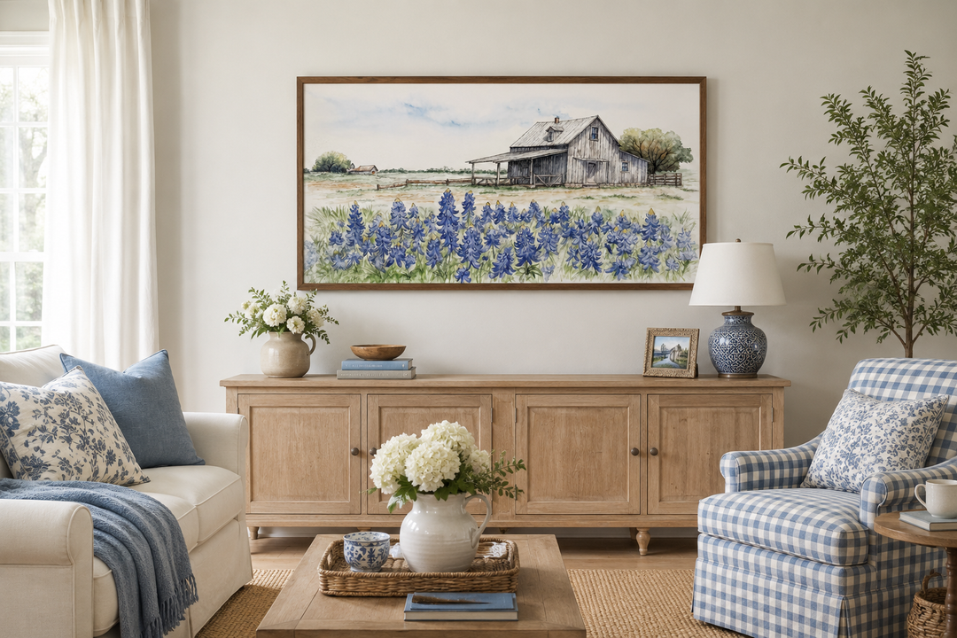 Framed horizontal canvas art of a rustic barn and bluebonnet field above a wooden sideboard.