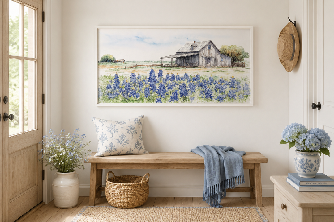 Rustic watercolor painting of a weathered barn in a field of bluebonnets, framed on a white wall.