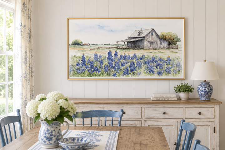 Framed horizontal canvas art of a rustic Texas barn in a field of bluebonnets above a sideboard.