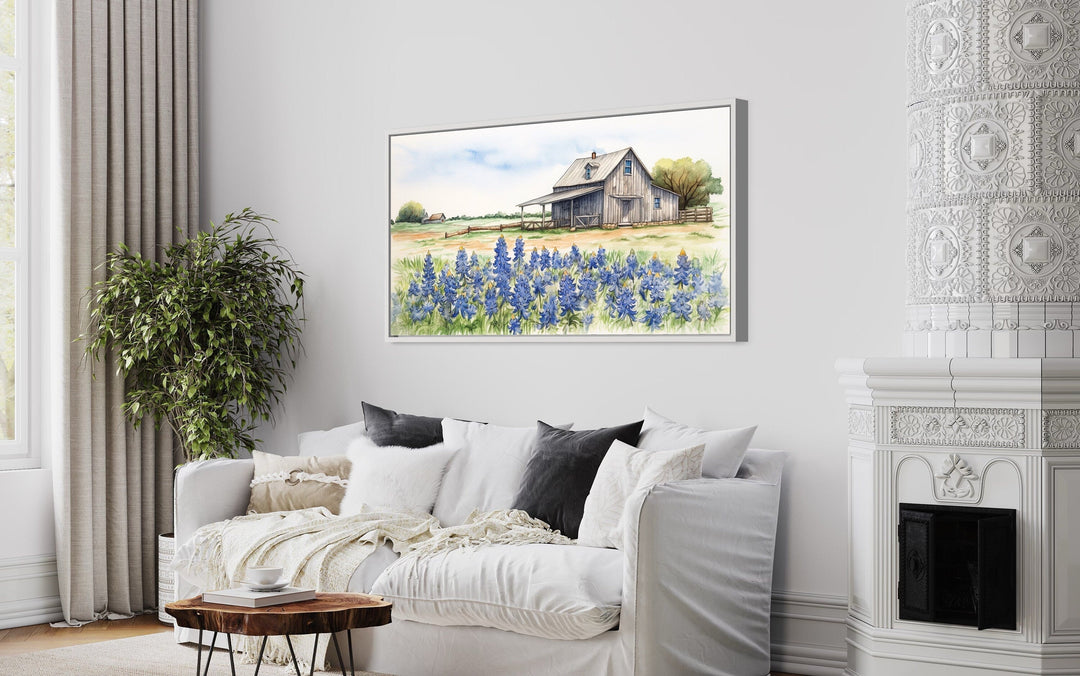 Texas barn wall art canvas featuring a rustic farmhouse and bluebonnet field above a white sofa.