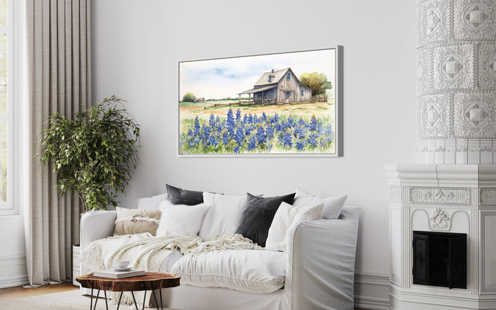 Texas barn wall art canvas featuring a rustic farmhouse and bluebonnet field above a white sofa.