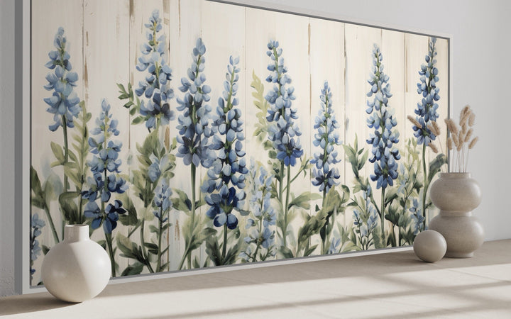 Rustic framed canvas wall art featuring bluebonnets painted on a light wood grain background.