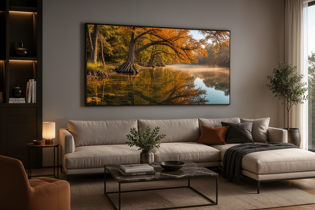 A large framed canvas print of a vibrant fall river landscape hangs above a modern sectional sofa.